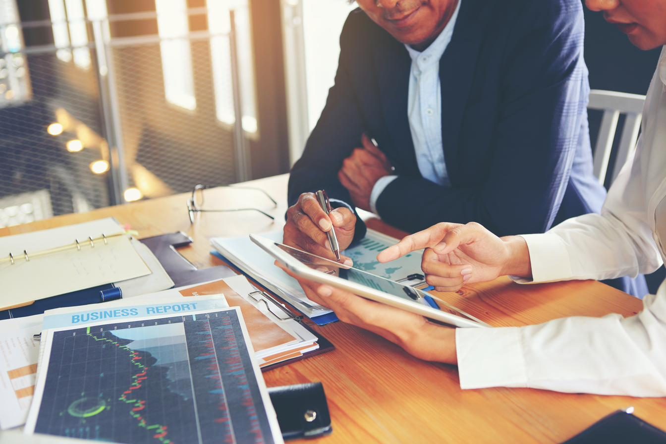 Two professionals reviewing a business performance report on a tablet
