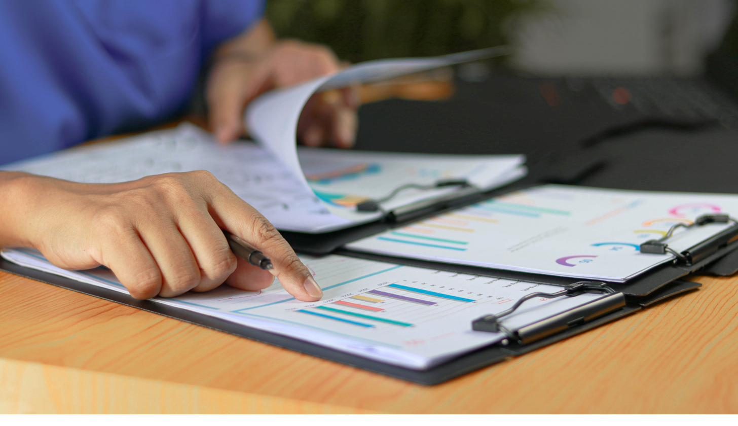 Hands reviewing printed operational charts and reports on a clipboard